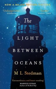 Silouette of a man standing in the top of a lighthouse srounded by a star-filled night.