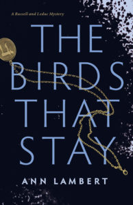 Front book cover: The Birds that Stay with a gold necklace running though it with a chai symbol.