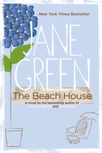 Blue front cover image of THe Beach House by Jane Green with an illustration of a blue flower and a chair and umbrella on the beach