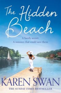 Front cover image of Karen Swan's The Hidden Beach of a woman at the end of a dock overlooking beautiful blue waters